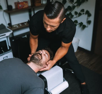 Dr. Michael VanDerschelden cradling the head of a patient lying on the table for a cervical adjustment